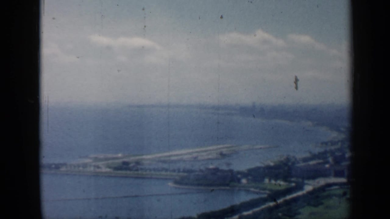 Soft aerial view of Lake Michigan shoreline with distant land and dark film borders.