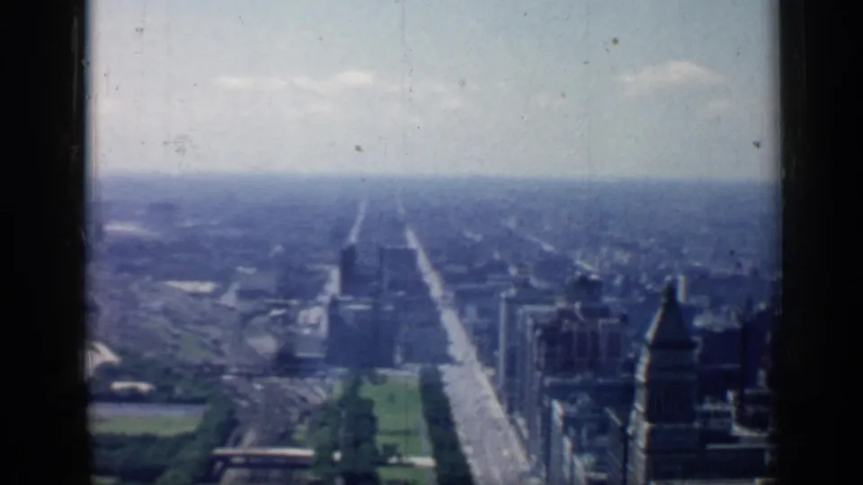 Chicago cityscape from a high vantage point in 1958, showing a straight avenue, tall buildings, green parkland, and hazy distance.