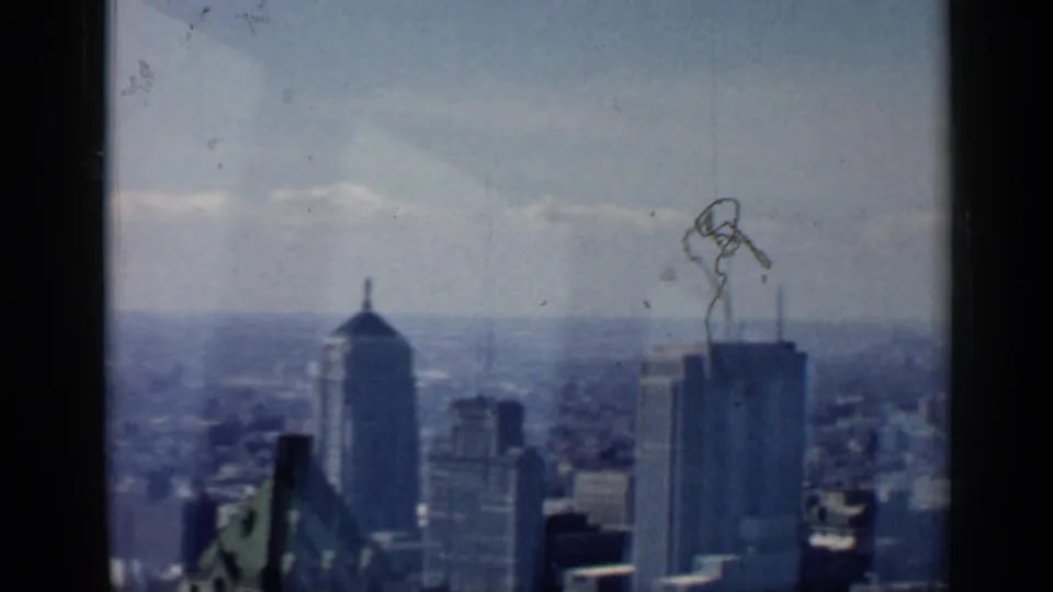 1958 Chicago skyline seen through soft, faded 8mm film, with tall buildings, a domed tower, distant haze, and contact-sheet wear.