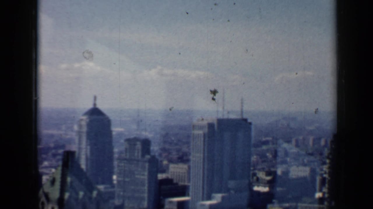 Distant Chicago skyline seen through a dark window frame under a hazy sky.