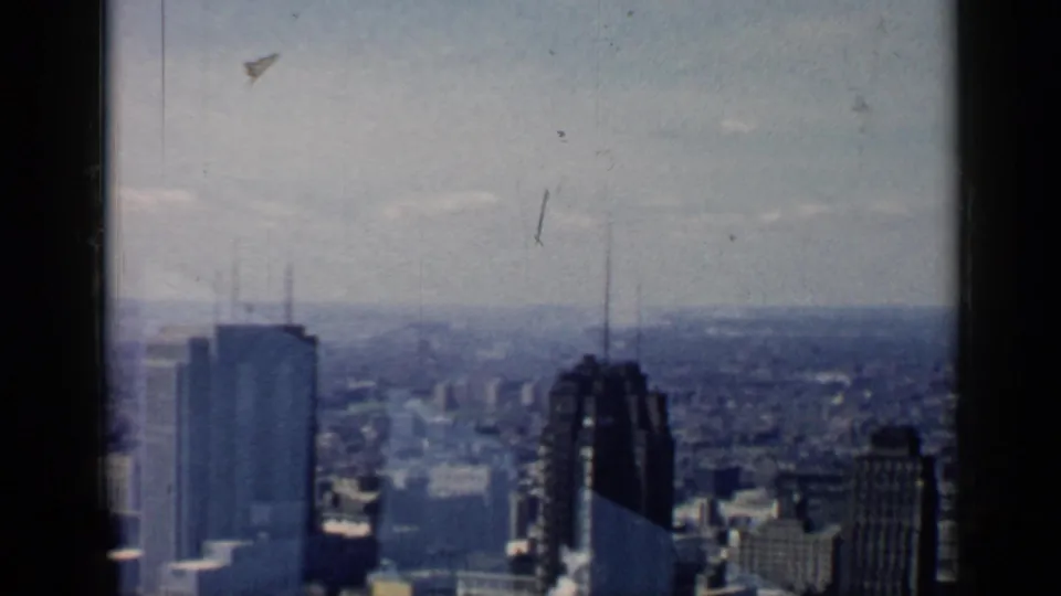 A 1958 Chicago cityscape from above, showing tall buildings, distant haze, and visible 8mm film wear.