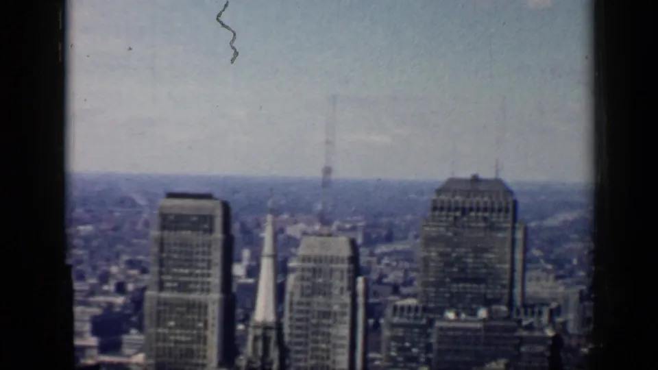 Mid-pan 1958 Chicago city view with office towers, a prominent steeple, distant neighborhoods, and scratched 8mm texture.