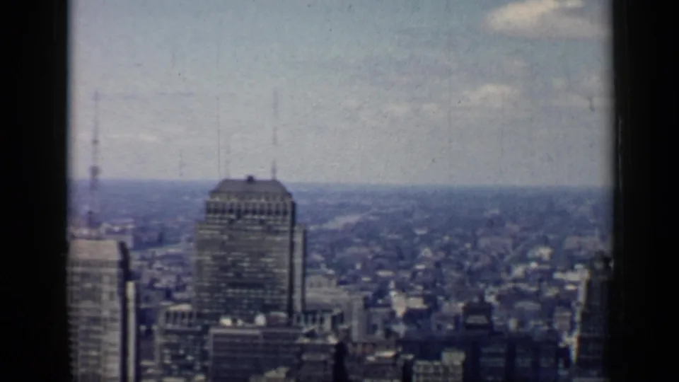 1958 Chicago skyline from a high viewpoint, with tall downtown buildings, distant urban blocks, cloudy sky, and dark window framing.