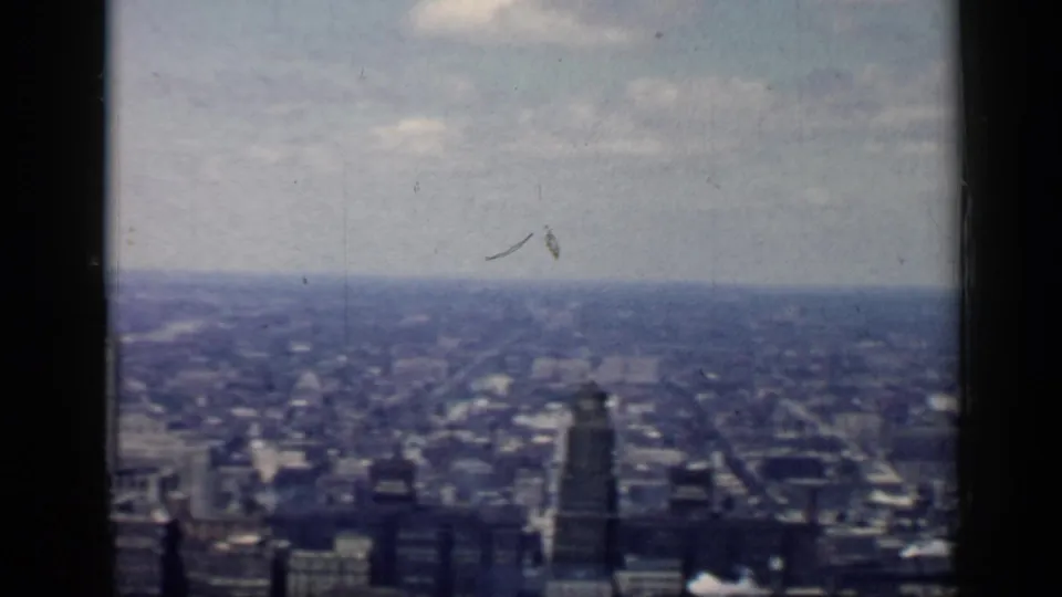 Wide 1958 Chicago city view across low-rise districts and distant towers, divided by a dark vertical window or frame bar.