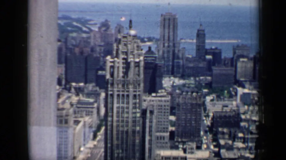 1958 Chicago skyline view with dense downtown towers, the Tribune Tower area, and lakefront water visible beyond the buildings.