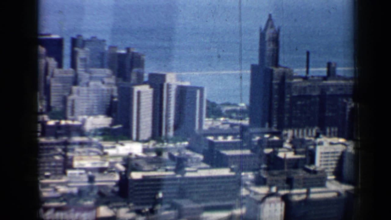 City skyline and lake with a tall pointed tower near the right side of the frame.