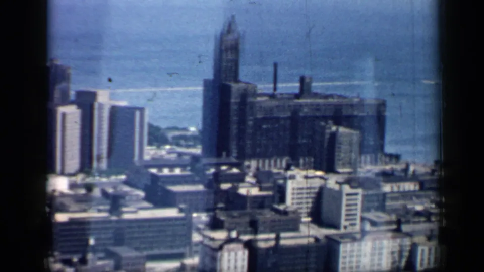 Aerial 8mm view of Chicago high-rises and rooftops with Lake Michigan behind the city core.