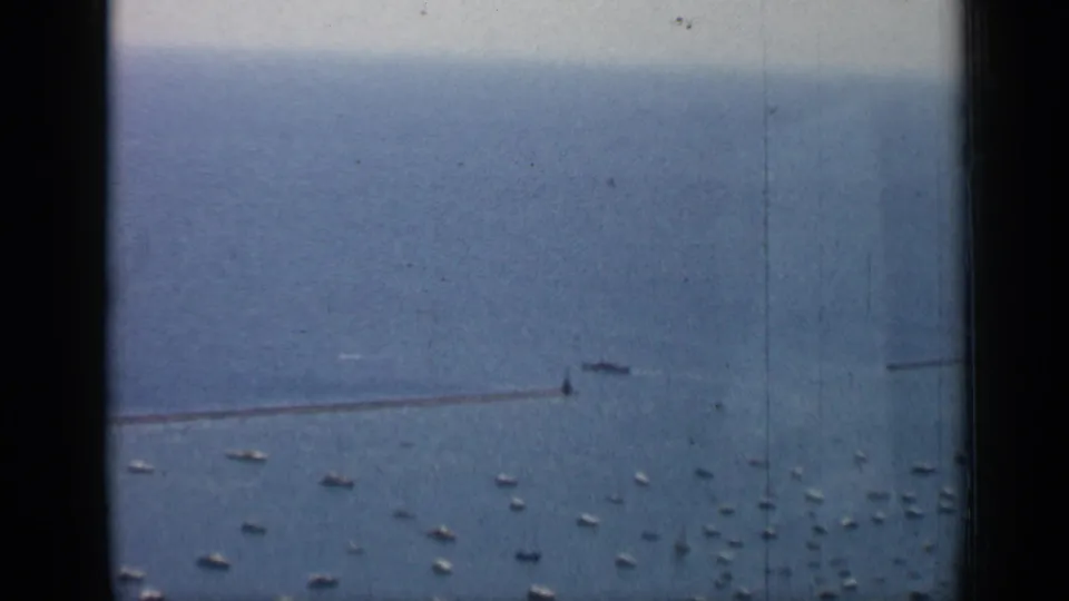 1958 Chicago lakefront view with a long breakwater, scattered small boats, open water, and dark window-frame edges.