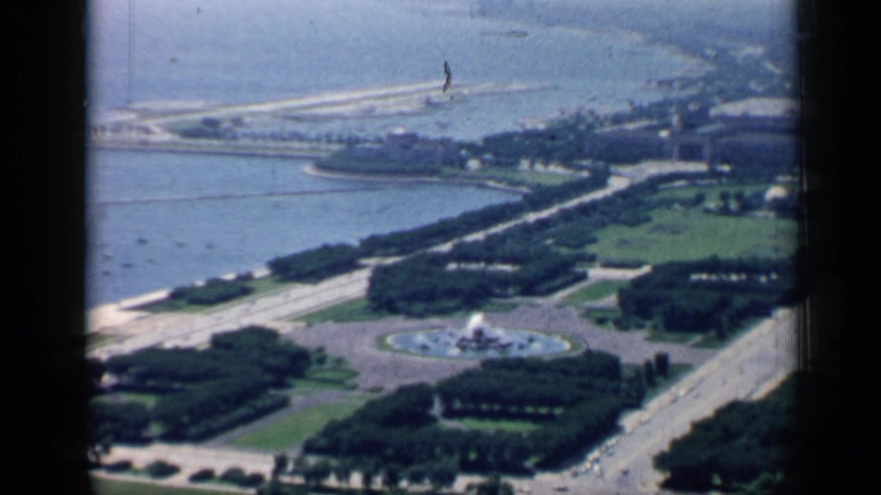 Similar elevated lakefront view with park trees, a fountain plaza, roads, and shoreline.