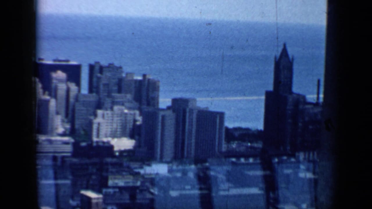 1958 Chicago skyline seen from a high vantage point, with Lake Michigan beyond and dark 8mm frame edges visible.