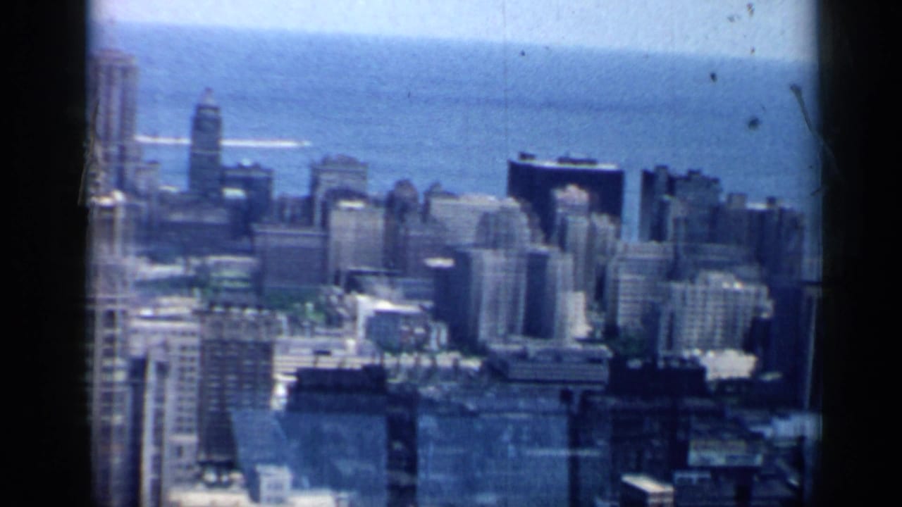 1958 Chicago city blocks and clustered high-rises are seen from above, with Lake Michigan forming the background.