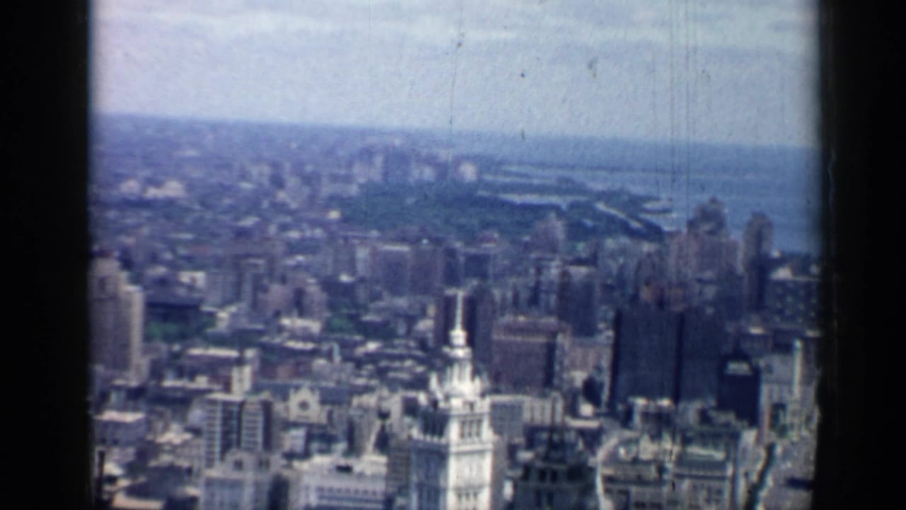 High-vantage 1958 Chicago view showing dense downtown buildings, lakefront water, and a hazy horizon.