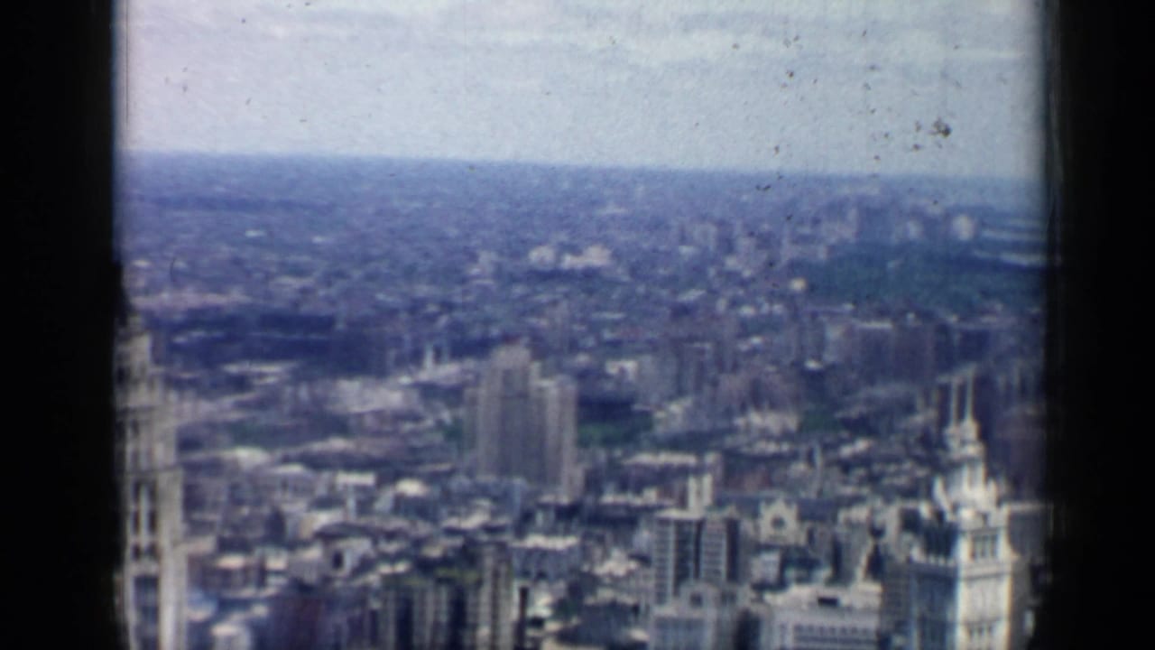 Soft 8mm view over 1958 Chicago rooftops, high-rises, and a distant urban horizon.