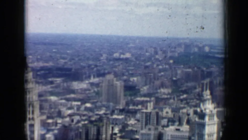 Soft 8mm view over 1958 Chicago rooftops, high-rises, and a distant urban horizon.