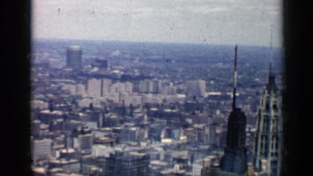 Wide skyline view with a tall antenna tower and dense city buildings.