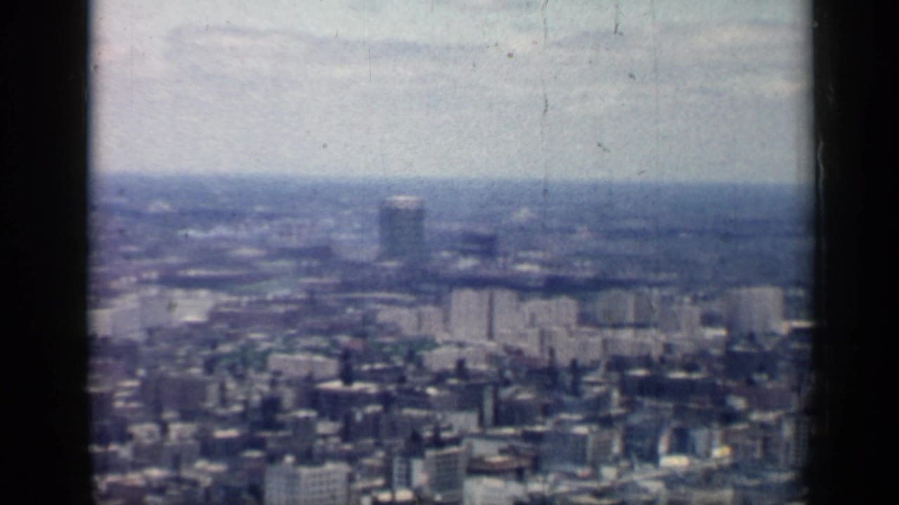 1958 Chicago home-movie view across a dense cityscape with distant towers, faded color, and visible 8mm film borders.
