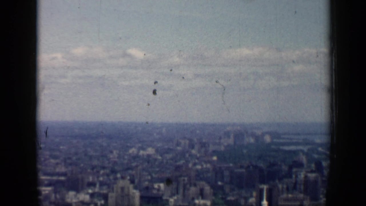 High view over Chicago in 1958, divided by a dark window frame with dense buildings fading into haze.