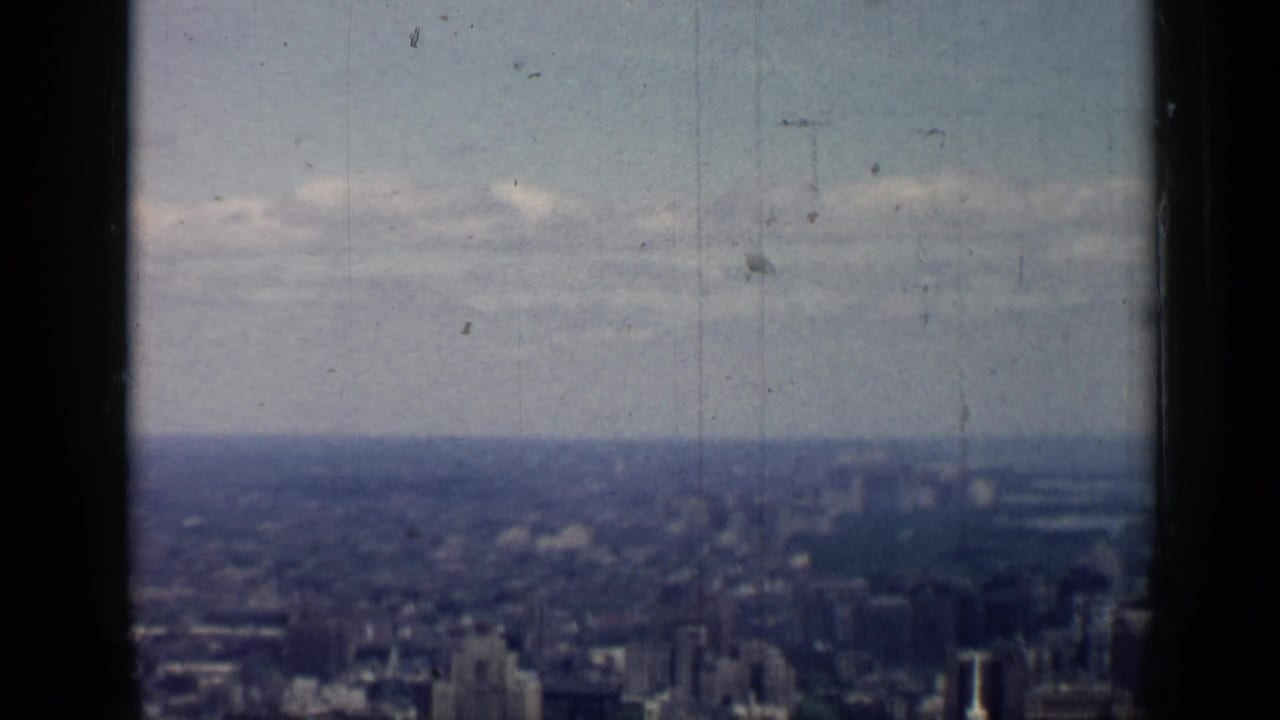 Muted 8mm view over the Chicago skyline, with low contrast, scratches, and a broad cloudy horizon.
