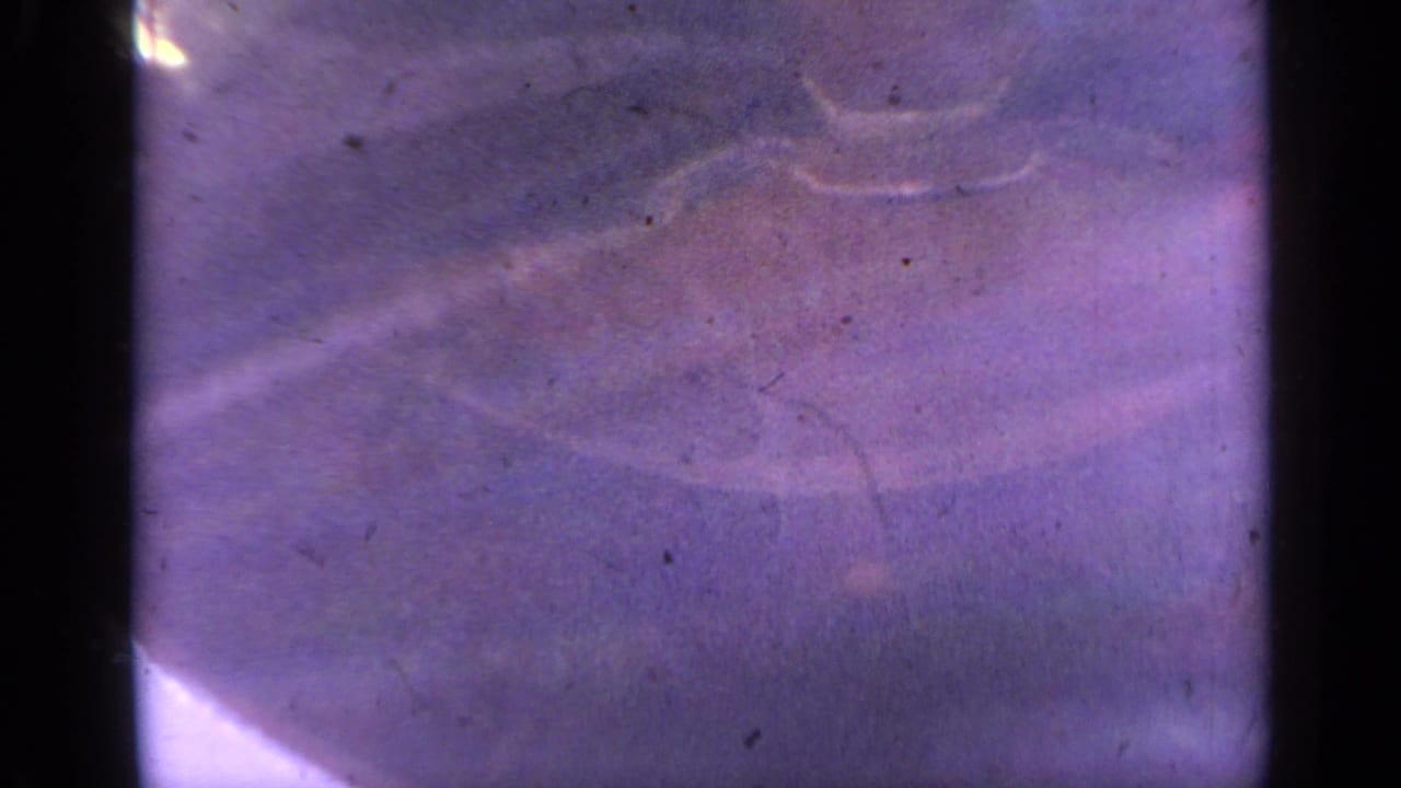The 8mm frame shows a soft shadowed lift form with flare and heavy purple color shift, consistent with aged 1959 Colorado home-movie footage.
