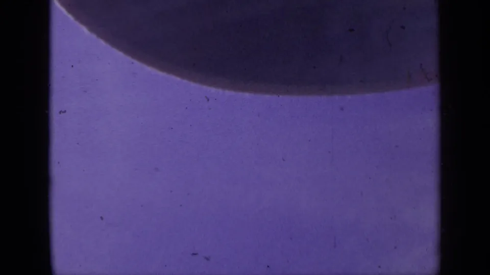 1959 Colorado 8mm frame showing a purple microscope field, a broad dark rounded form, and pronounced small-gauge film borders.