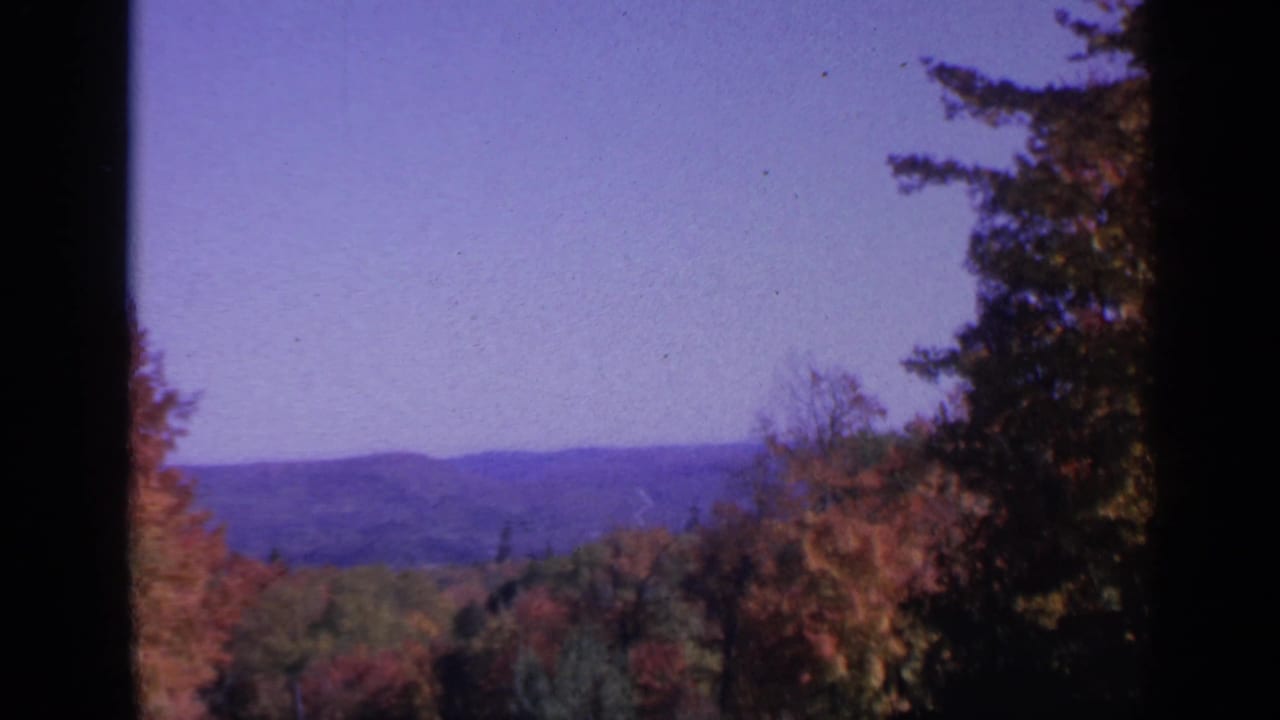Autumn trees and distant hills seen through dark window-like edges.