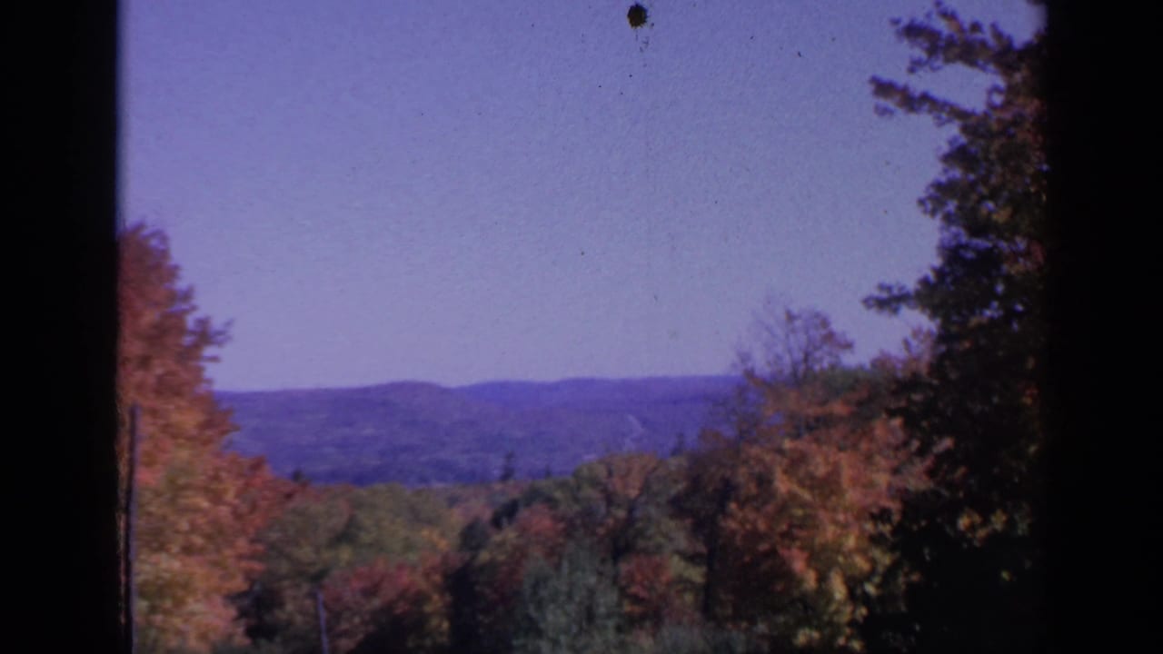 Window-framed Colorado landscape with rolling hills, mixed autumn foliage, evergreens, and soft 8mm color shift.