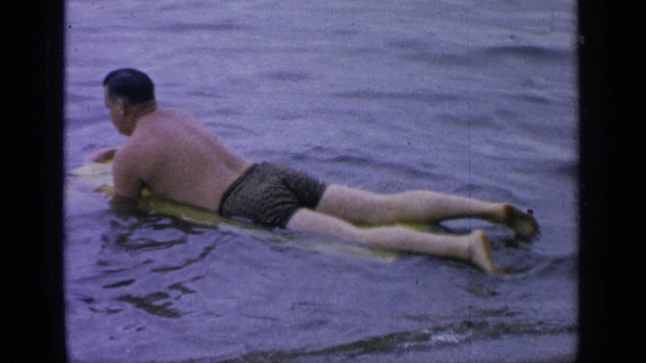 Man paddles away on a yellow board in rippled lake water.