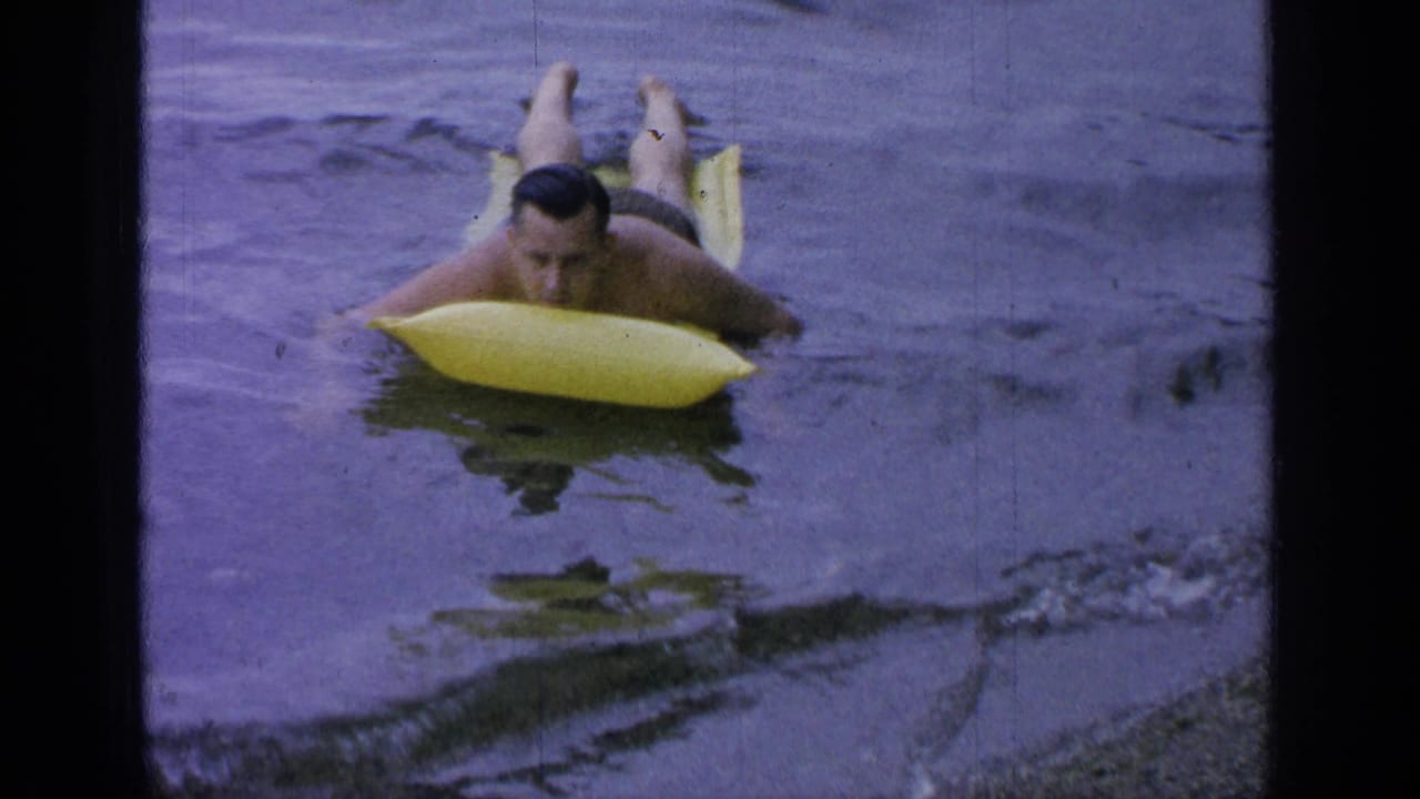 Man lying on a yellow inflatable raft in calm lake water.