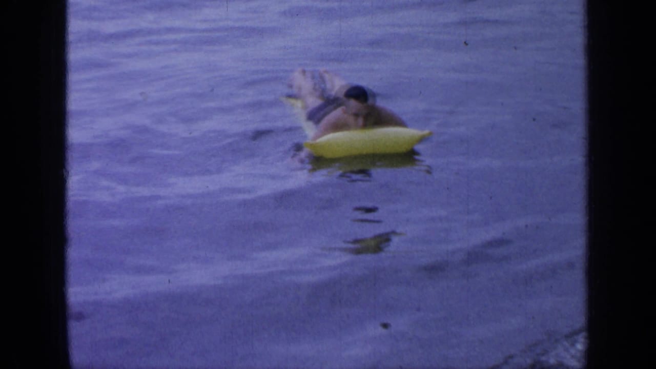 Man lying on a yellow inflatable raft in rippled lake water.