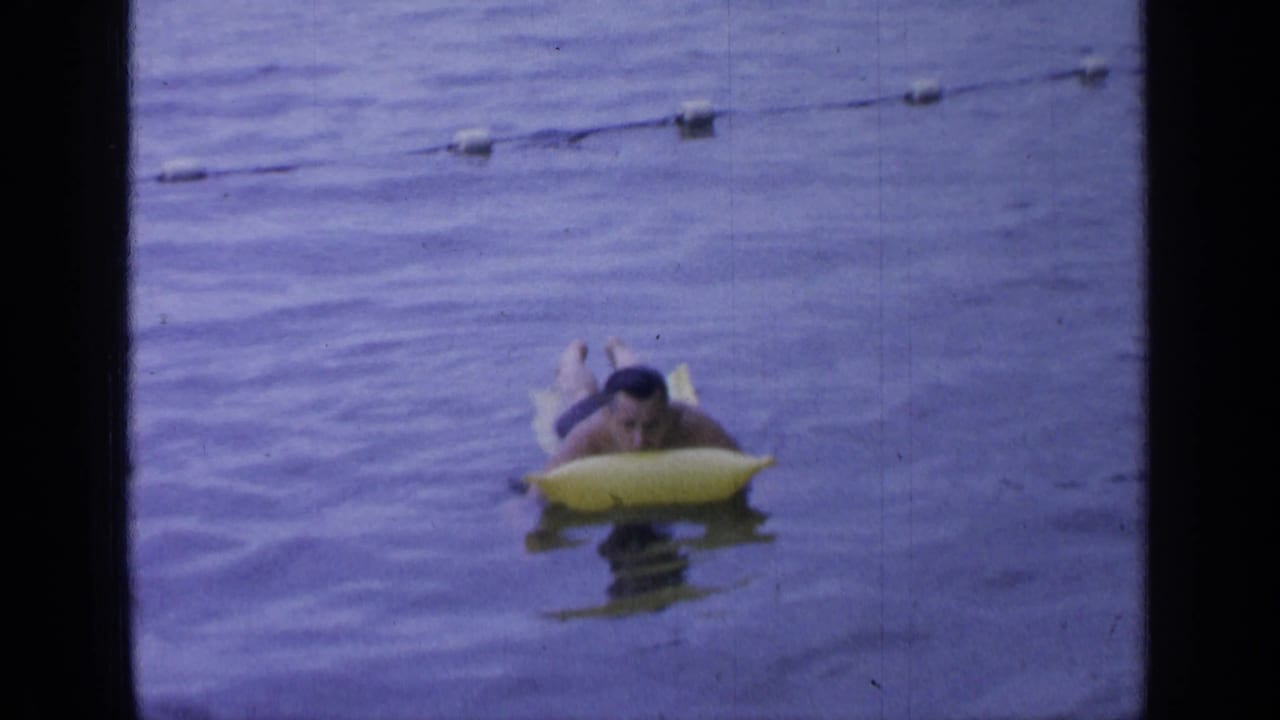 Man on a yellow raft floating near a line of buoys.