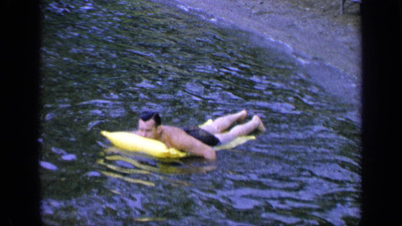 Man lying on a yellow inflatable board in rippled water.