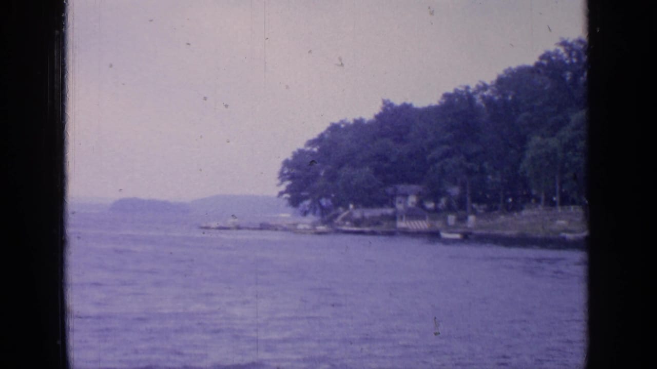 Greenwood Lake in 1964, seen in soft 8mm color with distant boats, wooded shoreline, and hazy hills beyond the water.