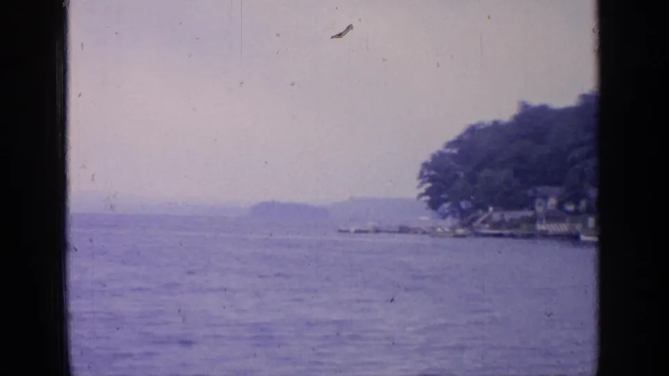 Soft 8mm frame of Greenwood Lake with open water, distant hills, and the wooded shoreline partly entering from the right.