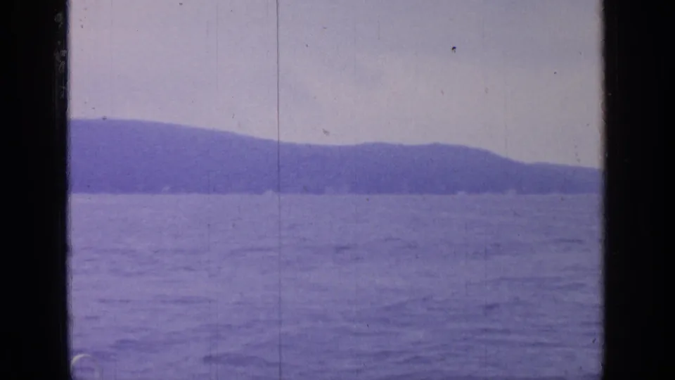 Greenwood Lake water and low wooded mountains appear beyond a dark window divider in faded 8mm color.