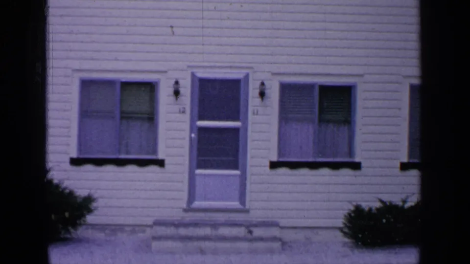 Greenwood Lake, New York, frame showing the numbered front entrance of a white clapboard residence with windows, steps, and shrubs.