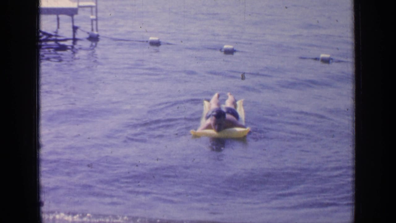 Man lying on a yellow inflatable float in roped-off lake water.