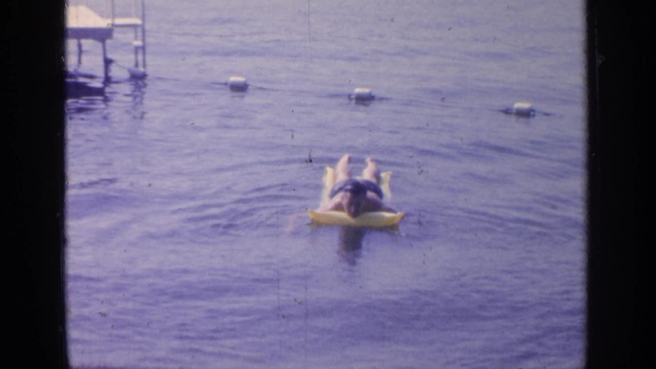The swimmer drifts farther across the buoy-marked water in this 1964 Greenwood Lake 8mm frame.