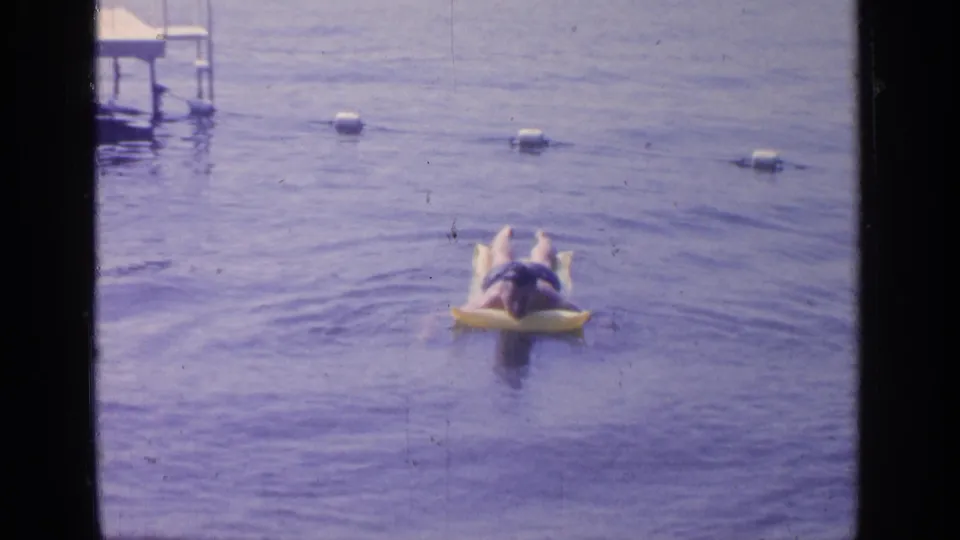 The swimmer drifts farther across the buoy-marked water in this 1964 Greenwood Lake 8mm frame.