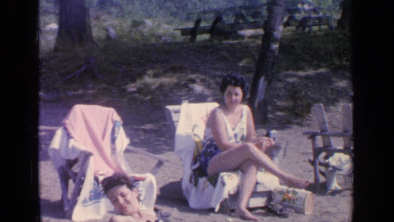 1964 Greenwood Lake frame with an adult woman seated in a swimsuit and another reclining low in the foreground.