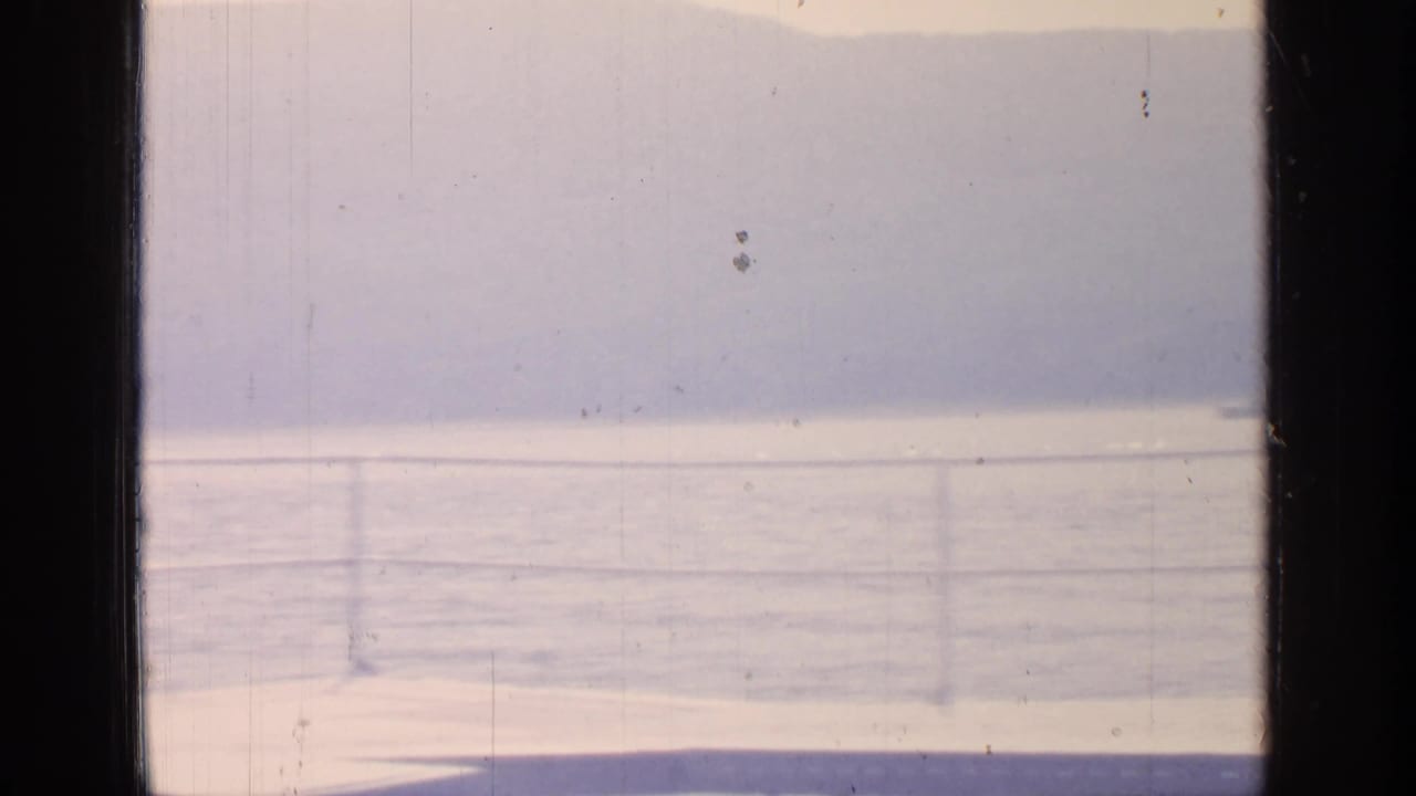 Bright lake and railing with distant hills, framed by the film edge and center divider.