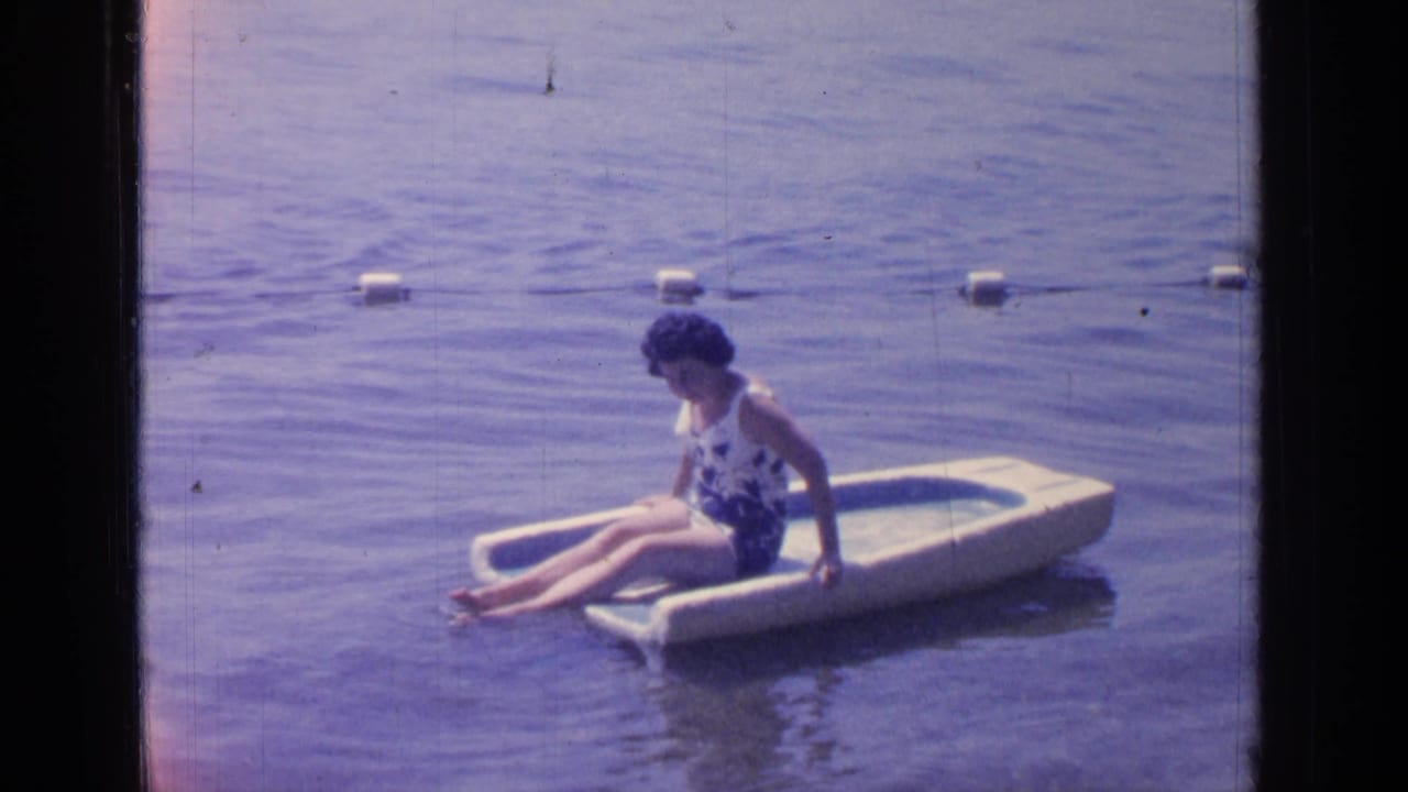 Woman sitting on a small float in lake water near a buoy rope.