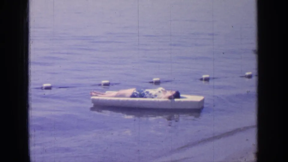 Greenwood Lake, New York, in 1964, with a man relaxing on a white floating platform in a quiet home-movie shot.