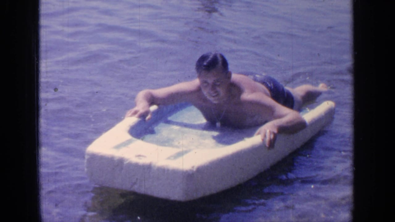 Adult man lying on a white foam float in lake water.