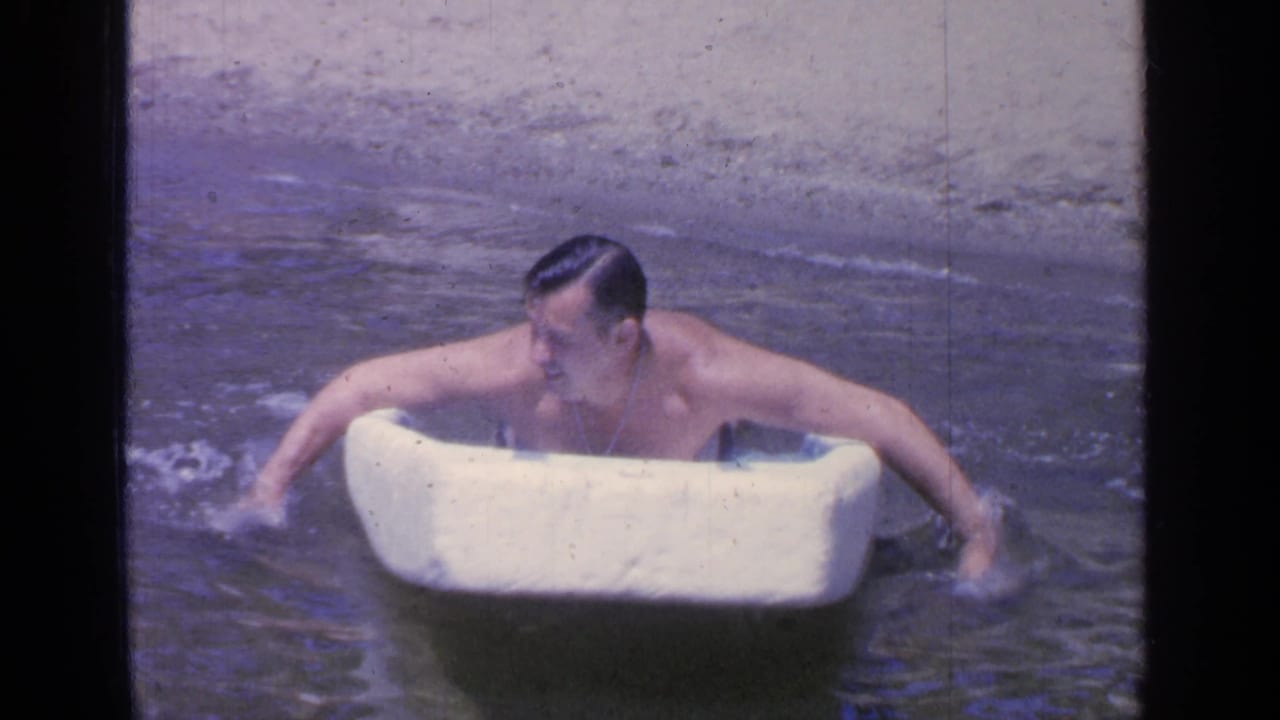 Man in lake water pushes forward on a white foam board.