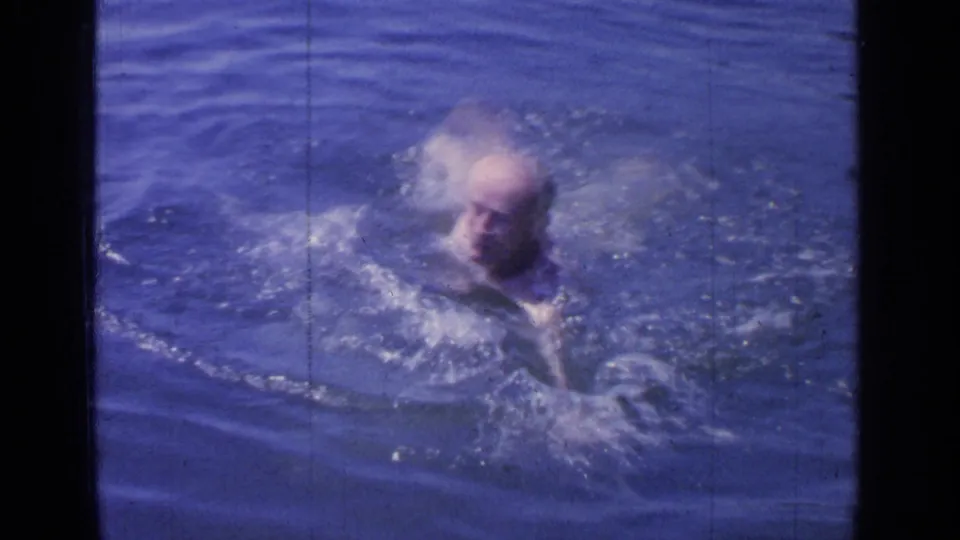 Motion-softened 1964 home-movie frame of the swimmer creating splashes in Greenwood Lake.