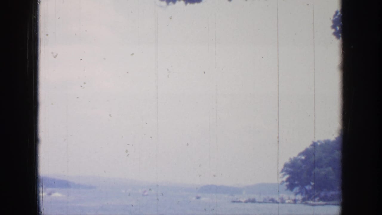 Lake and distant hills seen through a dark vertical window frame.