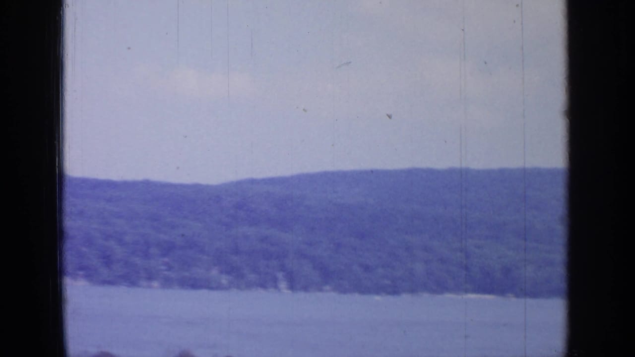 1964 Greenwood Lake view with blue water, forested hills, and dark edges from the boat or film gate.