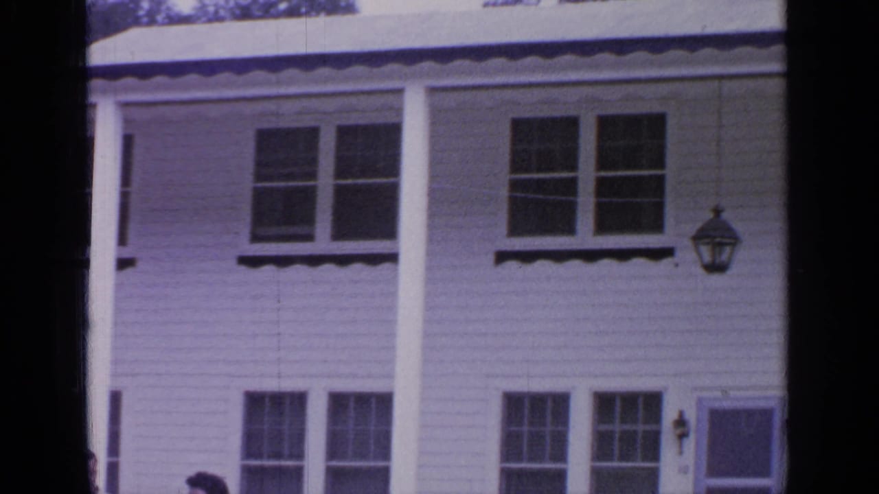 1964 Greenwood Lake exterior view of a white clapboard house with columns, upper windows, and a doorway at the right edge.