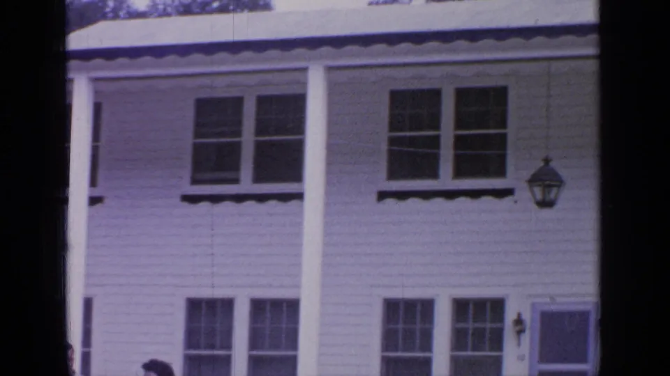 1964 Greenwood Lake exterior view of a white clapboard house with columns, upper windows, and a doorway at the right edge.