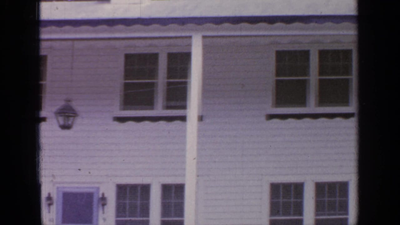 White clapboard house facade with windows, porch columns, and a front door partly visible.